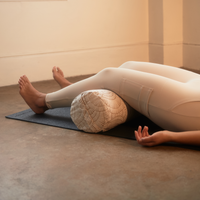 Person laying on floor with knees over bolster